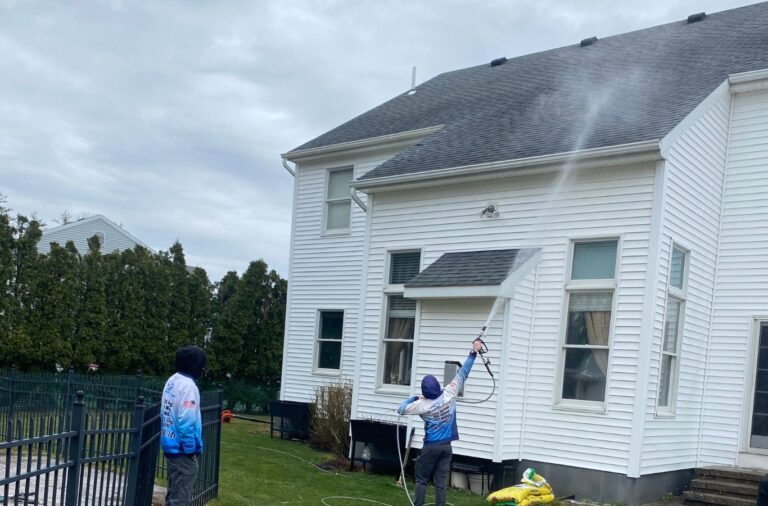 A team member from Upstate Softwash cleaning the exterior of a home in Halfmoon, NY, highlighting the advantages of regular maintenance.​